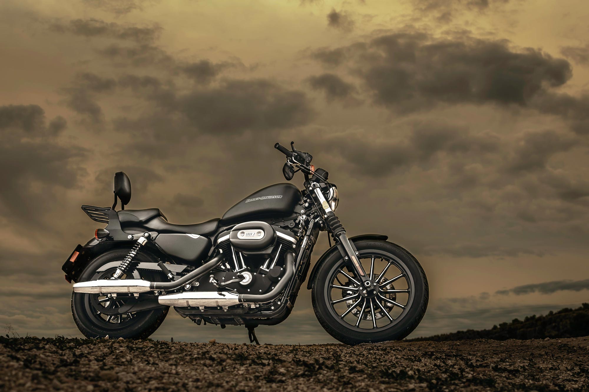 A black motorcycle is parked on a dirt road, its tire pressure matching the recommended values on the Harley Davidson chart.